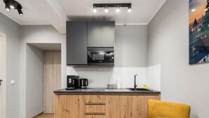 A modern kitchen with a wooden countertop, a built-in oven, and a sink. There is a yellow chair and a table with a leaf-patterned coaster. - Underground Basilica Apartment (Kraków)