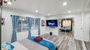 A hotel room with a bed, a TV, a mirror, and a window with curtains. - The Shalimar Casita, Fits 6 Guests, Smart Tvs, Remodeled Unit, Full Size Kitchen (Riverside)