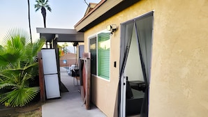 A residential property with a covered patio, a sliding glass door, and a small outdoor seating area. - The Shalimar Casita, Fits 6 Guests, Smart Tvs, Remodeled Unit, Full Size Kitchen (Riverside)