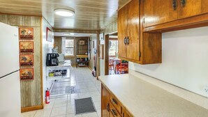 Una cocina compacta con armarios de madera, una cafetera y un pequeño comedor con mesa y sillas.
