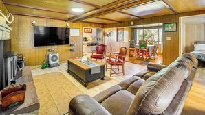 Una sala de estar acogedora con un sofá de cuero, un televisor de pantalla plana y un techo de madera.