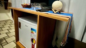 Une petite cuisine équipée d’un réfrigérateur, d’un four à micro-ondes et d’une petite machine à café.