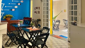 Un coin repas avec un mur bleu, une table entourée de chaises et une vue sur la plage par la fenêtre.
