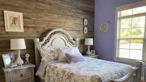 A bedroom with a wooden headboard, floral bedding, two bedside tables with lamps, and a window with blinds. - Spacious 5-bedroom, 3-bathroom Masters ready house.  14 miles from Nationals GC. (Evans)