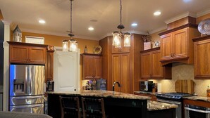 A modern kitchen with wooden cabinets, stainless steel appliances, and a central island with bar stools. - Spacious 5-bedroom, 3-bathroom Masters ready house.  14 miles from Nationals GC. (Evans)