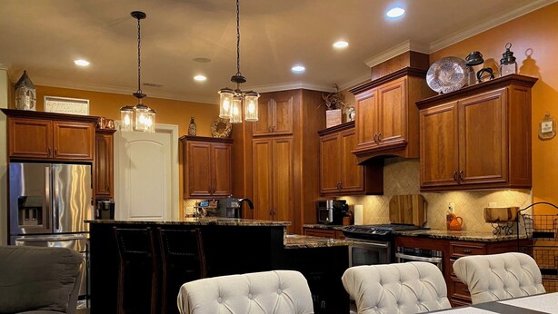 A modern kitchen with wooden cabinets, stainless steel appliances, and a dining area with a table and chairs. - Spacious 5-bedroom, 3-bathroom Masters ready house.  14 miles from Nationals GC. (Evans)