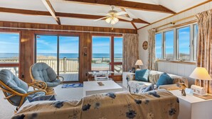 A room with a balcony overlooking the beach, furnished with a sofa, chairs, and a small table. - 7050 Sailor's Rest at Nags Head * Oceanfront (Nags Head)