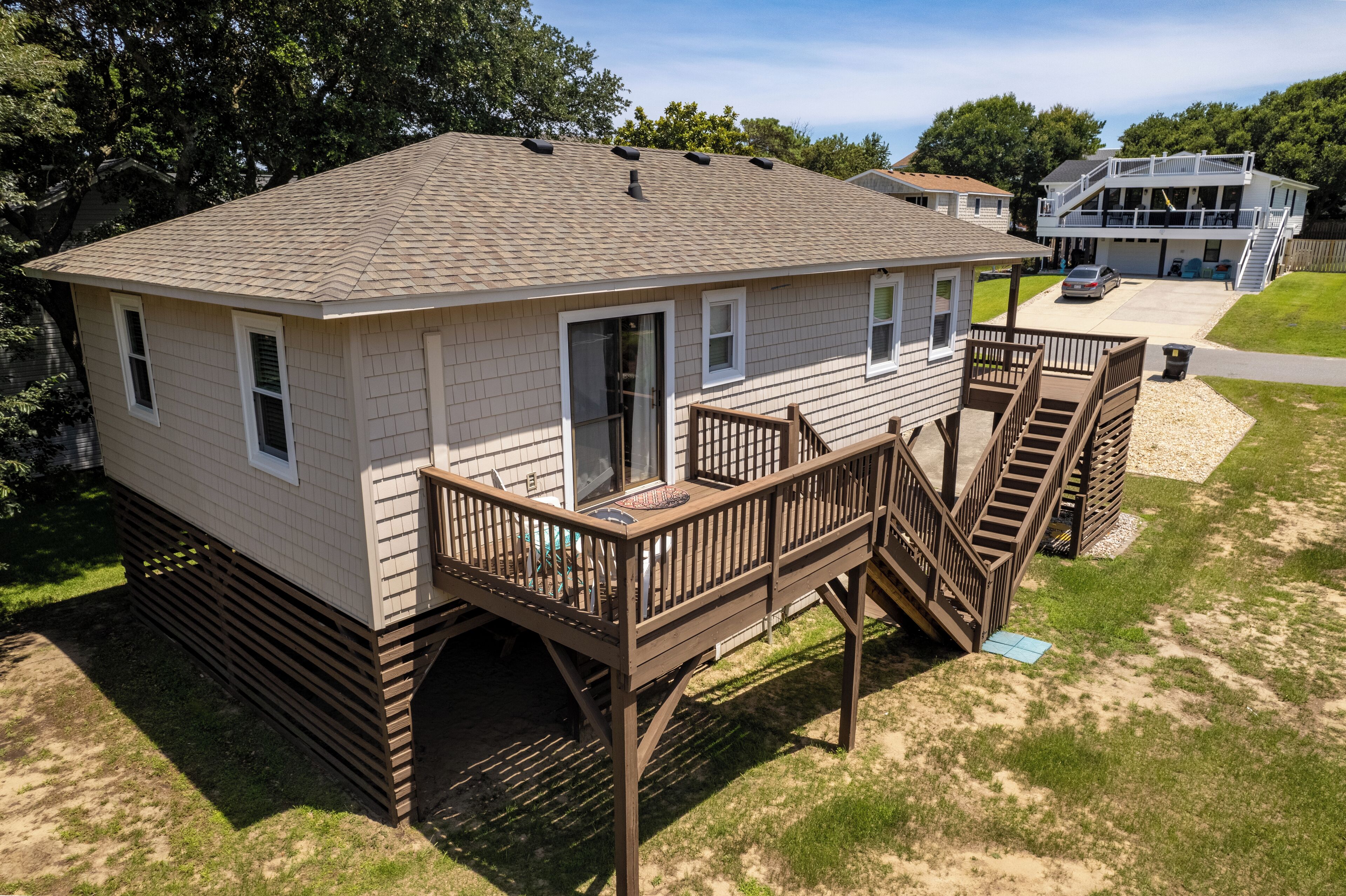 A two-story house with a deck and stairs, a garage, and a covered outdoor area.