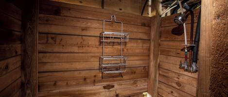 Een houten interieur met een metalen rek aan de muur en zichtbare leidingen.