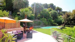 Eine Terrassenfläche mit Gartenmöbeln, einem Swimmingpool und üppiger Bepflanzung.
