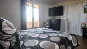 Ein Schlafzimmer mit einem Bett, einem an der Wand befestigten Fernseher, einem Kleiderschrank und einer Tür.