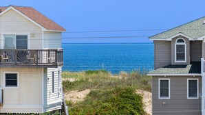 A beachfront house with a balcony overlooking the ocean.