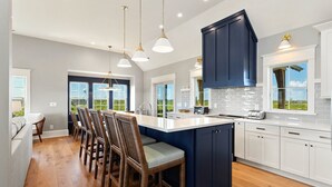 A modern kitchen with a central island, white cabinetry, and a view of the outdoors.