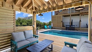 A wooden deck with a pool, outdoor furniture, and a covered area with a ceiling.