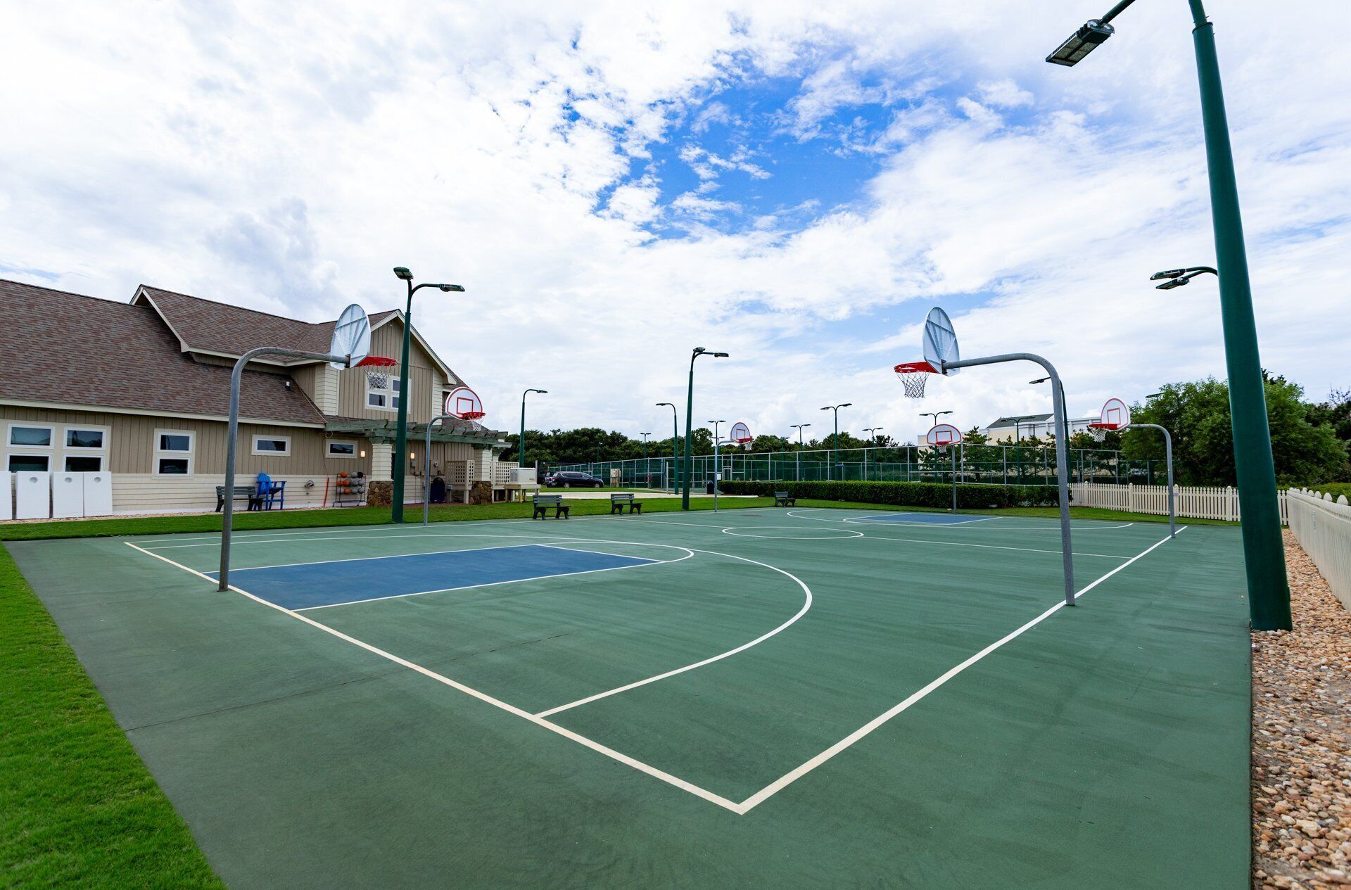 Un terrain de basket en plein air, avec une maison en arrière-plan.
