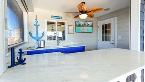 A kitchen with a white countertop, blue cabinets, and a ceiling fan.