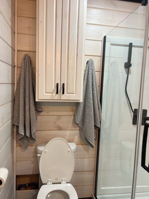 Een douche, handdoeken, zeep, toiletpapier