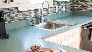 A kitchen with a sink, a coffee maker, a cutting board with cheese, olives, and cured meat. - Peaceful Pretty Art and Cinema Reclining Couches (Ferndale)