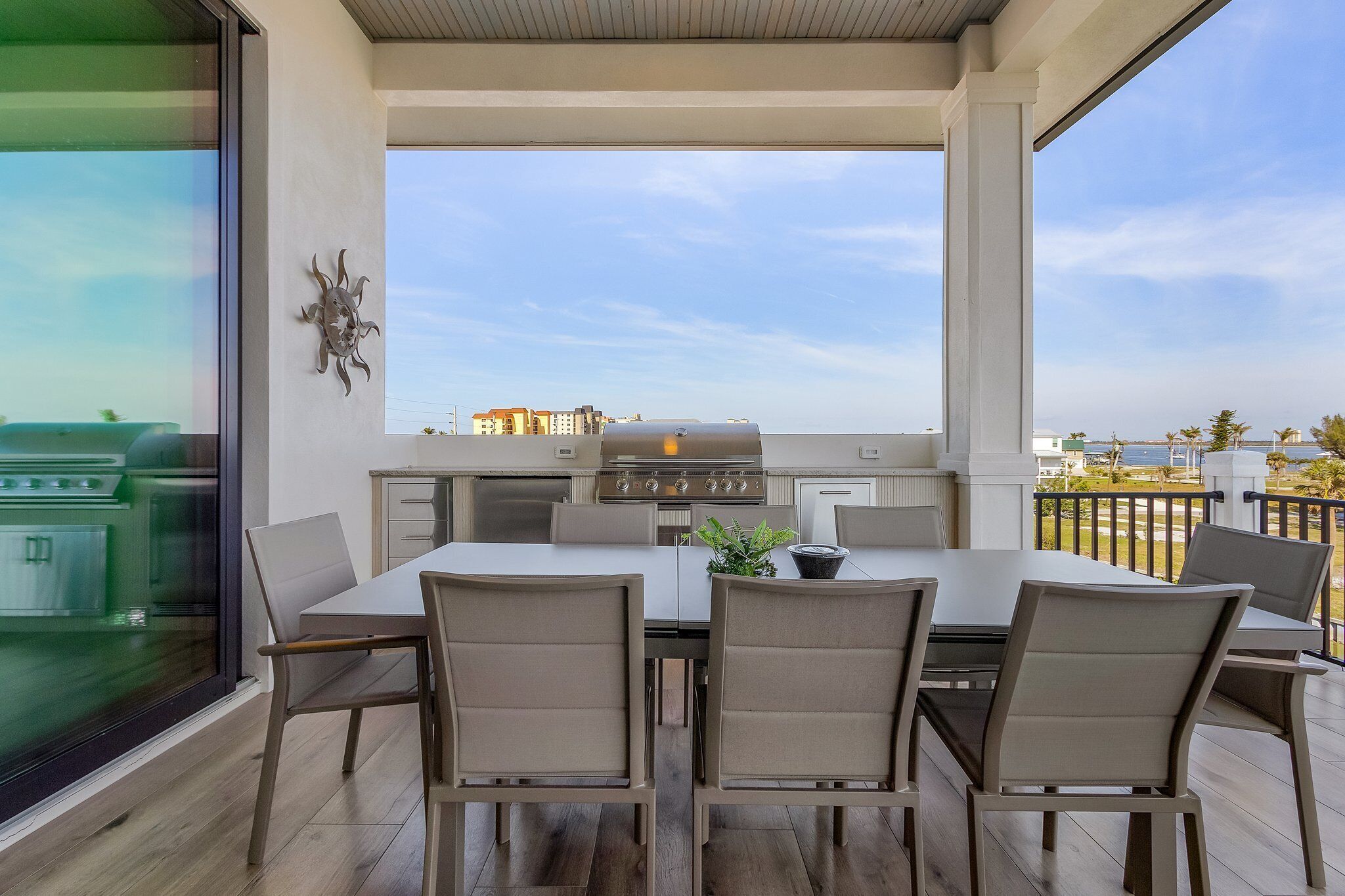 An outdoor patio with a dining table and chairs, a grill, and a view of the cityscape.