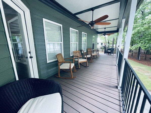 A covered porch with wooden chairs and a ceiling fan.