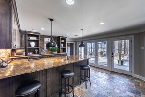 A kitchen with dark wood cabinets, a granite countertop, and a large island with stools.