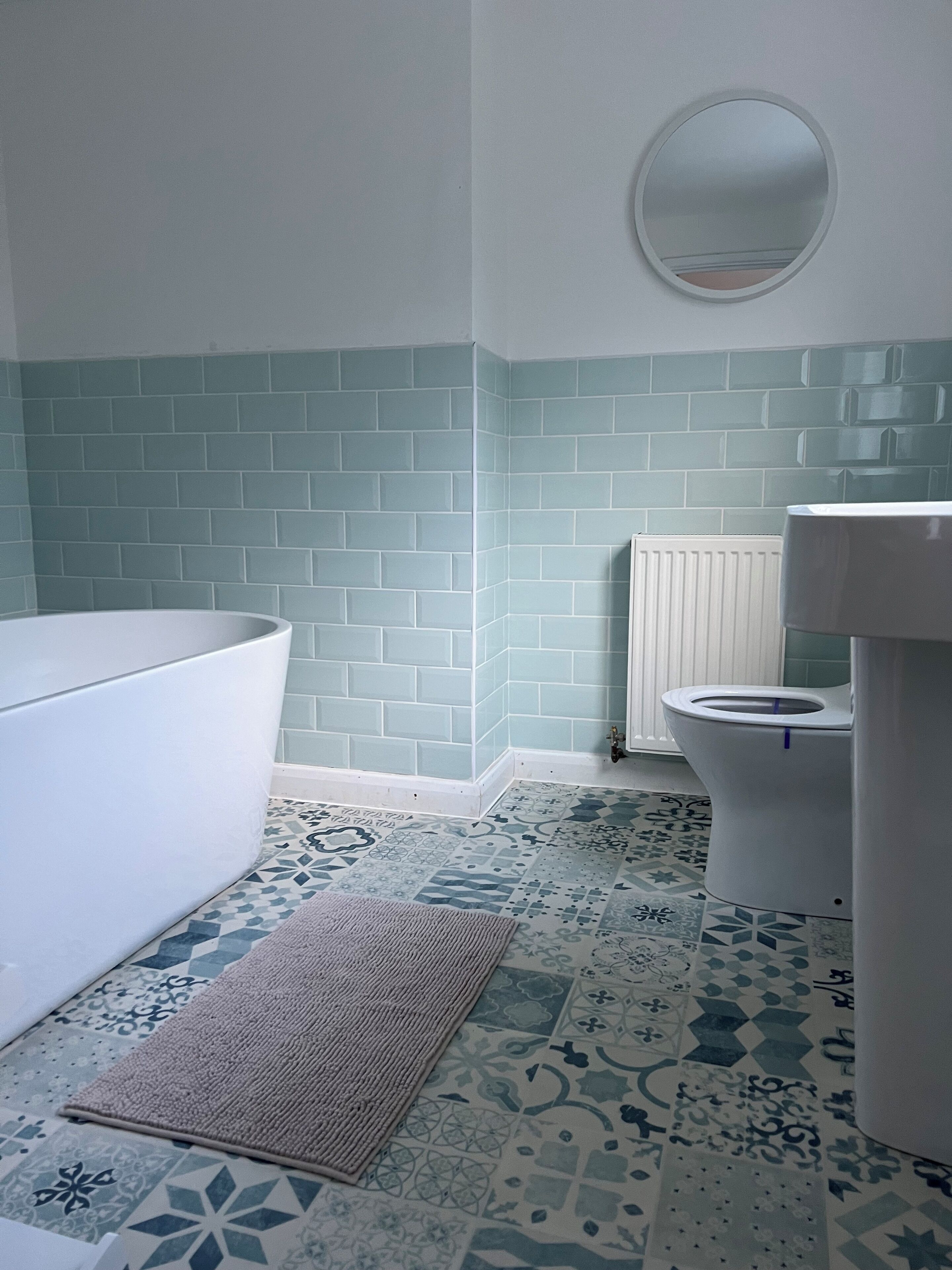 A bathroom with a white bathtub, a toilet, and a sink. The walls are tiled in a light blue and white pattern.