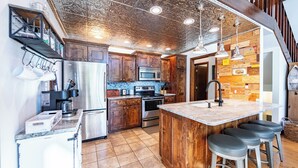 A kitchen with wooden cabinets, a stainless steel refrigerator, a microwave, and a large island with bar stools. - Sparta Escape a perfect getaway (Sparta)