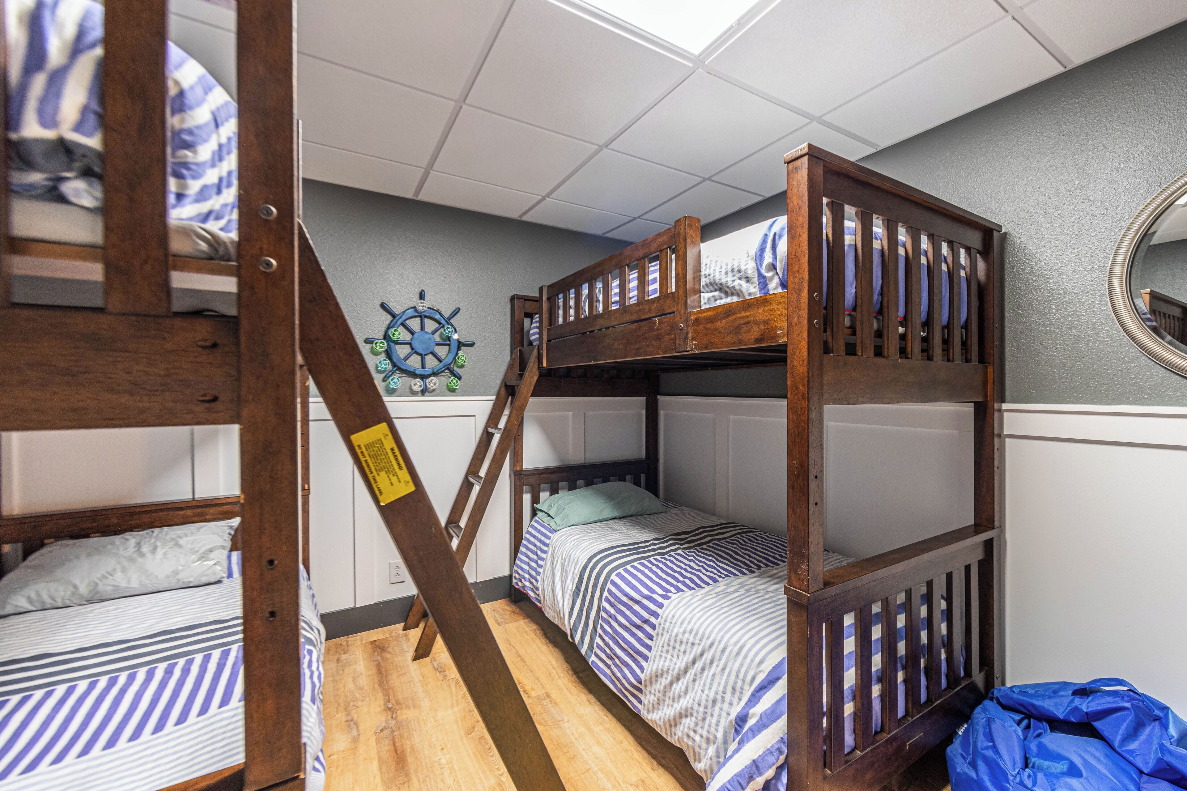 A bunk bed room with a ship's wheel decoration on the wall.