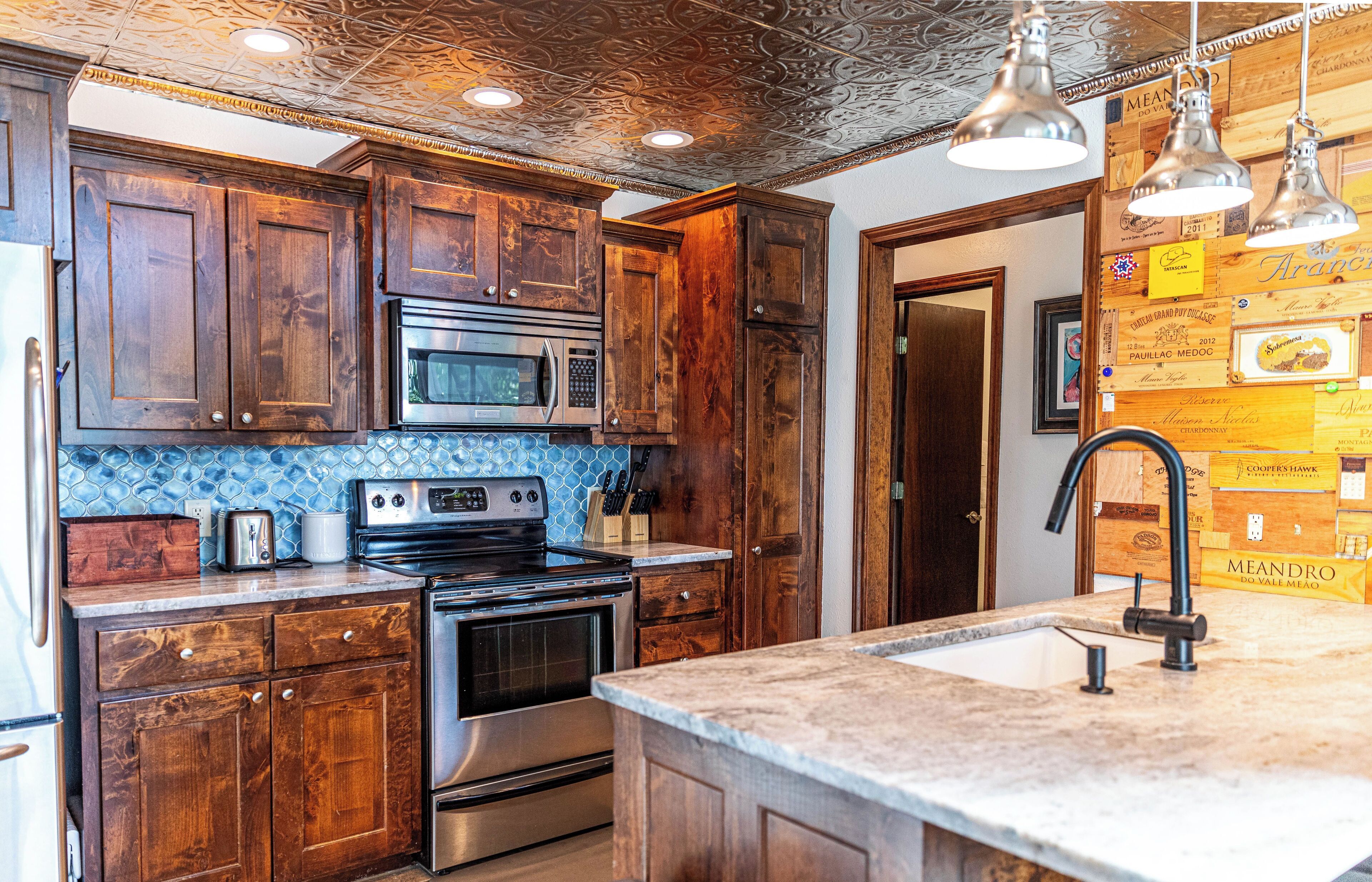 A kitchen with wooden cabinets, a stainless steel stove, a microwave, and a sink.