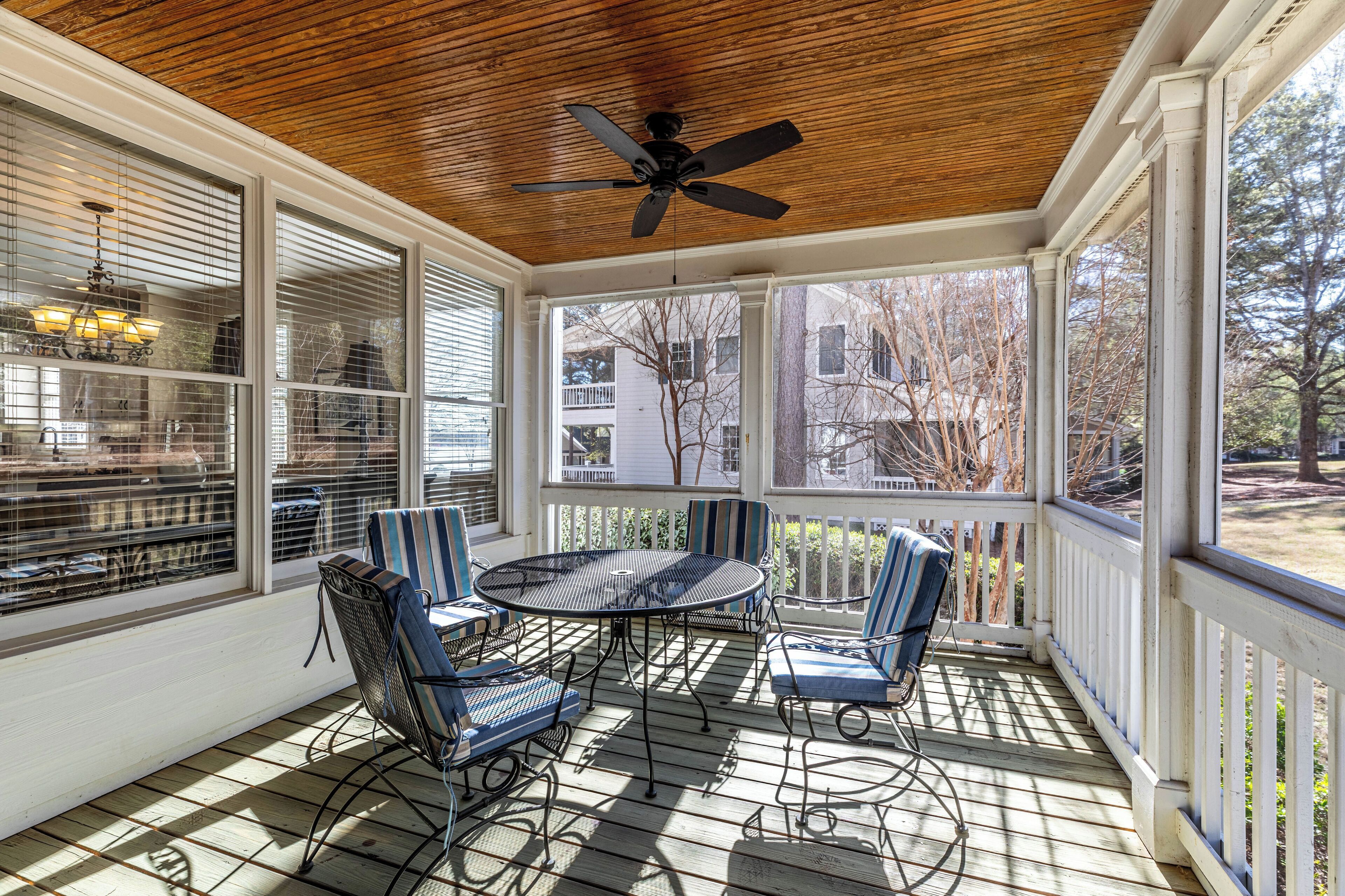 A covered patio with a ceiling fan, a round table, and four chairs.