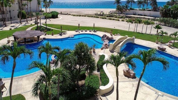 A resort with a large central pool, palm trees, and a beach view. - Paradise Awaits: Beachfront, 2 Master Suites in San José del Cabo (San José del Cabo)