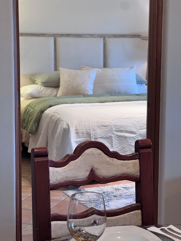 Un dormitorio con una cama, almohadas y un vaso de agua sobre una mesa.