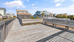 Un muelle de madera que conduce a casas frente a la playa bajo un cielo despejado.