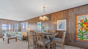 Un comedor con mesa y sillas de madera, una araña y un vitral.