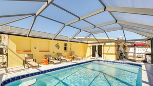 Un espace piscine doté de chaises longues, d’une zone abritée et d’une piscine à l’eau d’un bleu limpide.