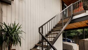Una escalera con barandilla metálica que conduce a una terraza de madera.