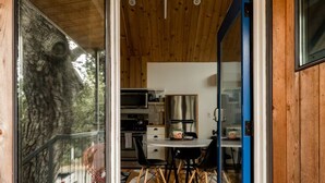 Una cabaña de madera con un ventanal de vidrio que da a un comedor con mesa y sillas.