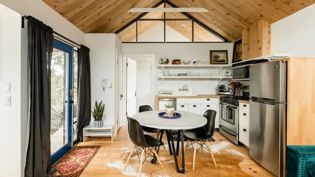 Una cocina moderna con una isla central, electrodomésticos de acero inoxidable y techo de madera.