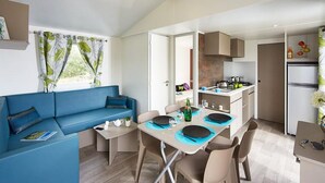 Un espacio habitable pequeño con comedor, kitchenette y un sofá azul.
