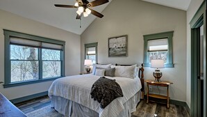 A bedroom with a large bed, two bedside tables with lamps, a ceiling fan, and two windows with blinds. - The Owlery, Walk to Town (Highlands)