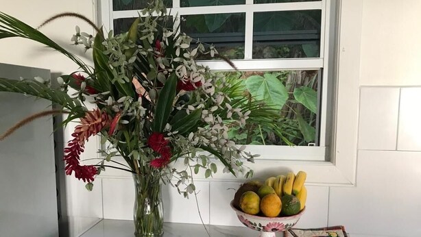 A kitchen counter with a vase of flowers and a bowl of fruit.