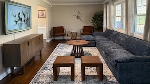 A living room with a sofa, two chairs, a coffee table, a TV, and a ceiling fan. - Creekside Escape – Spacious 5BR with Pool & BBQ (Columbus)