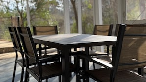 A covered patio with a table and chairs, surrounded by trees. - Creekside Escape – Spacious 5BR with Pool & BBQ (Columbus)