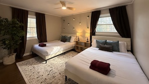 A hotel room with two beds, a ceiling fan, bedside lamps, a potted plant, and a patterned rug. - Creekside Escape – Spacious 5BR with Pool & BBQ (Columbus)