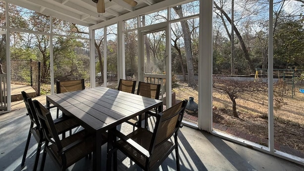 A covered patio with a table and chairs, large windows, and a ceiling fan. - Creekside Escape – Spacious 5BR with Pool & BBQ (Columbus)