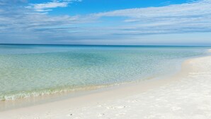 A beach with clear shallow waters and a sandy shore.