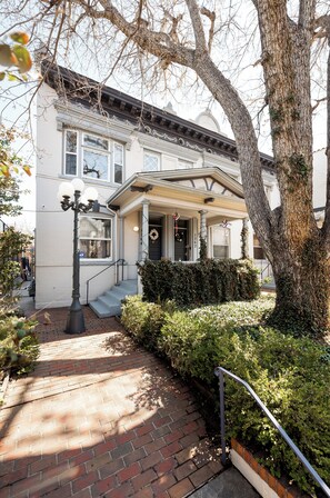 A white building with a porch, steps leading to the entrance, and a tree in the foreground. -   Classic Row Home Patio, Porch & Garage. Walk to Downtown & Convention (Denver)
