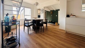 Une salle à manger spacieuse avec un plafond haut, un plancher en bois et un lustre moderne.