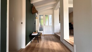 Un hall d’entrée spacieux, doté d’un plancher en bois, de murs blancs et d’une porte donnant sur une autre pièce.