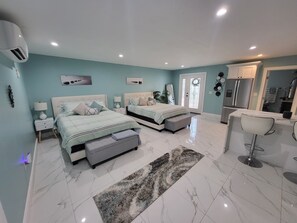 Une chambre avec deux lits, une salle de bain et un coin cuisine.